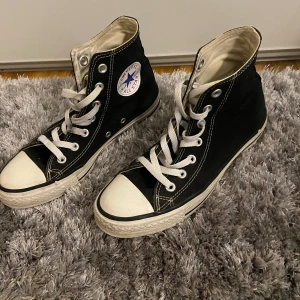 Svarta Converse All Star sneakers - Säljer ett par klassiska svarta Converse All Star sneakers i bra skick. De har den ikoniska vita tåhättan och snörning. Perfekta för vardagsbruk och passar till nästan allt. Lite slitna på ens märket men fortfarande i fint skick. Storleken är 37. 💓💓💓