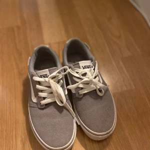Grå sneakers från Vans - Säljer ett par grå Vans sneakers i bra skick. De har en klassisk design med vit sula och snörning. Perfekta för vardagsbruk och ger en skön och avslappnad stil. Passar till det mesta och är superbekväma att ha på sig hela dagen.