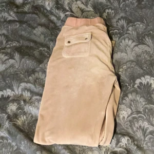  mjukisbyxor från Juicy Couture - Säljer ett par superbekväma mjukisbyxor från Juicy Couture. De har en mjuk resår i midjan och praktiska fickor med knappar bak. Perfekta för en avslappnad dag hemma säljer dom billigt eftersom att dom är lite missfärgade 