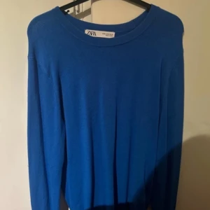 Blå tröja från Zara - Säljer en snygg blå tröja från Zara i storlek M. Perfekt för både vardag och festliga tillfällen. Tröjan har en enkel design med långa ärmar och rund halsringning. Passar bra till jeans eller kjol för en stilren look. 
