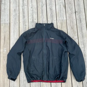 Tommy Hilfiger Windbreaker - Otroligt skön vintage windbreaker från Tommy Hilfiger, har också en regnluva som går att vika fram från kragen. Fin mörkblå färg med vinröda detaljer och foder!  Skriv om du har några frågor!😊