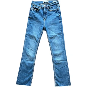 Blå bootcut jeans från Zara - Säljer ett par snygga blå bootcut jeans från Zara. De är aldrig använda och därför i nyskick. Nertill har de ingen uppsydd kant utan är snarare lite mer ”trådig” nedtill i designen. Storlek: 32 Midjemått: 29cm Innerbenslängd: 66cm