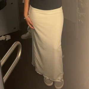 Beige långkjol - Säljer en stilren vit långkjol som passar perfekt för både vardag och fest. Kjolen har en enkel och elegant design som gör den lätt att matcha med olika toppar och accessoarer. Perfekt för en avslappnad men ändå chic look!