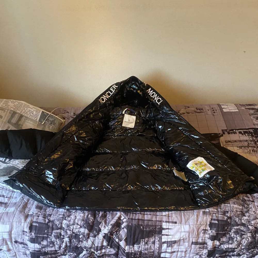 Säljer en snygg svart pufferjacka från Moncler. Den är perfekt för vintern med sitt varma och quiltade material. Jackan har en dragkedja framtill och Moncler-loggan på ärmen. Insidan är glansig och har Moncler-tryck runt kragen. Superbra skick och redo för kalla dagar!. Jackor.