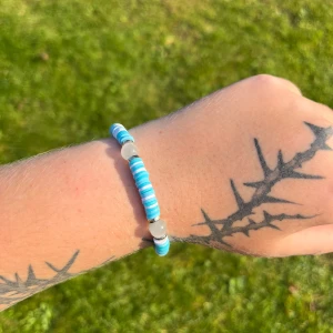 Blått och vitt armband med pärlor - Säljer ett superfint armband med blå och vita pärlor. Det är elastiskt och passar perfekt för sommaren. Armbandet har en fräsch och strandig känsla, perfekt för att liva upp vilken outfit som helst!