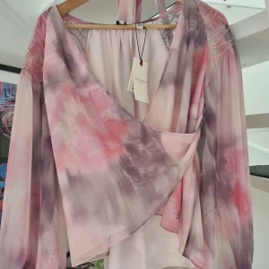 Ted Baker London blus strl 38 - Säljer en oanvänd blus med tagg kvar. Den blev för stor innan jag hann använda den.  Strl 38.  https://www.tedbaker.com/eu/p/Womens/Outlet/Clothing/Tops-and-T-Shirts/EMILIAH-Wrap-Blouse-With-Smocked-Shoulder