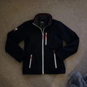 Helly hansen jacka - Helly hansen jacka. Storlek xs. Mörkblå med röd vita detaljer.