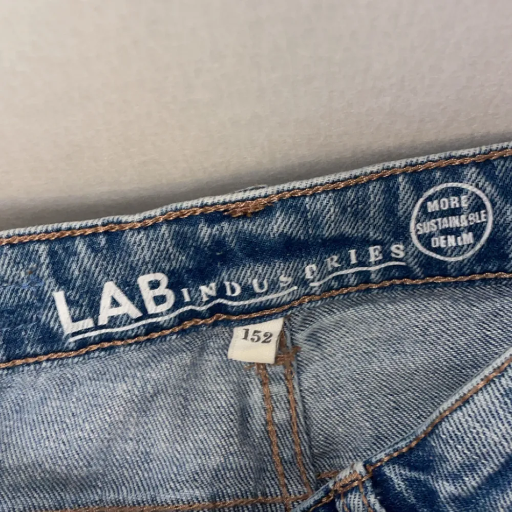Säljer ett par blå jeans från LAB Industries i storlek 152. Jeansen har en klassisk straight passform med slitna detaljer på benen för en trendig look. Perfekta för en avslappnad stil.. Farkut & Housut.
