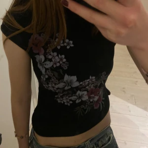 Svart blommig topp - Köptes här på plick men får tyvärr ingen användning för den! Står ingen storlek men skulle säga att den passar xs/m😊