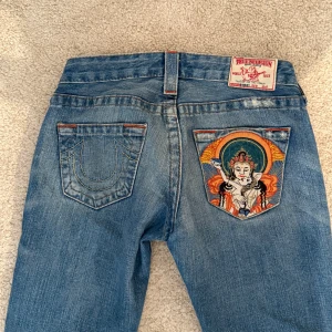 True Religion jeans - Snygga blå jeans från True Religion med en unik broderad detalj på bakfickan. De har en låg midja och en bootcut-stil. Jag är 164 ungefär och dem är lite för långa. (Säljs inte längre) pris går att diskutera