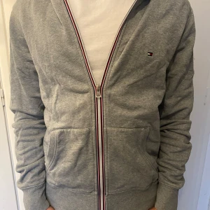 Tommy Hilfiger zip - En skön och stilren zip hoodie från Tommy Hilfiger utan några defekter. 8/10.  Modellen på bilden är 178 cm lång och väger 66 kg. Hör av er vid fler frågor.