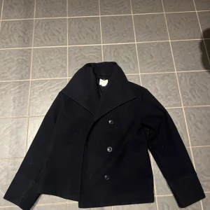 kappa från Gina Tricot - Snygg marinblå kappa från Gina Tricot med dubbelknäppning och klassisk krage. Perfekt för kyligare dagar och ger en stilren look. Är en vårjacka och en höstjacka! Passar bra till både vardag och mer uppklädda tillfällen. Passar mig som har xs till s 