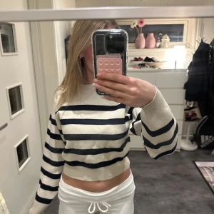 Randig tröja från Zara - Säljer en snygg randig tröja från Zara i svart och vit. Tröjan är croppad med långa ärmar och har en ribbad kant vid halsen. Perfekt för en stilren look!