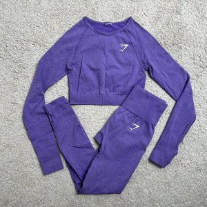 Lila träningsset från Gymshark - Säljer ett snyggt lila träningsset från Gymshark. Setet består av en långärmad croppad topp och matchande tights. Perfekt för gymmet!