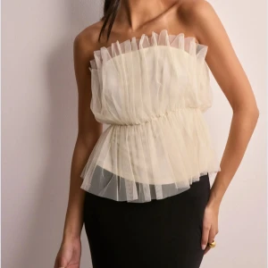 Vit axelbandslös tylltop  - Säljer en fin vit axelbandslös topp med volangdetaljer. Den är elastisk i midjan för en bekväm passform och passar så bra till lite festligare tillfällen🤩