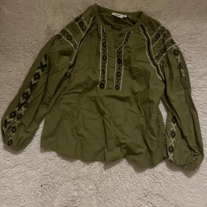 En grön blus som är i bra skick - Grön med lite detaljer och är i bra skick, passar mig dom har storlek 14/16 i detta märke, möts helst upp