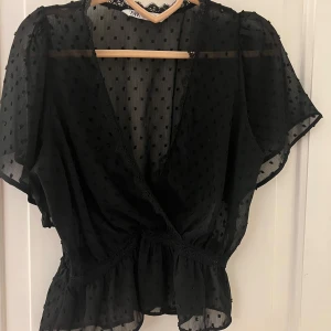 Svart Zara blus - Snygg svart blus från Zara med prickigt mönster och v-ringad design🥰Blusen har korta ärmar och volangdetaljer vid midjan. Den är i nyskick och priset kan diskuteras vid snabb affär💕💕