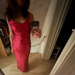 Röd paljettklänning - Säljer nu min helt oanvända balklänning. Den är en snygg mörkrosa-glittrig långklänning. Klänningen har en slits , vilket ger en elegant look. Perfekt för festliga tillfällen och balen.