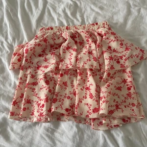 Blommig kjol från Shein - Jätte gullig blommig kjol från Shein i rött och vitt/beige. Kjolen har volanger och ett elastiskt midjeband för en bekväm passform. Knappt änvänd💕