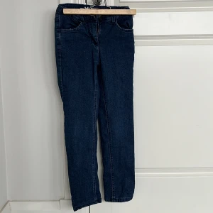 Mörkblå jeans från John Baner - Säljer ett par mörkblå jeans från John Baner i storlek 134. De har en klassisk design med fem fickor och knappstängning. Perfekta för vardagsbruk och passar till det mesta. Insidan är fodrad med en härlig rosa färg för extra komfort.