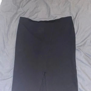 Svart kjol med slits - Elegant svart kjol med en diskret slits framtill. Perfekt för en stilren look.