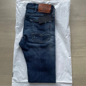 Blå jeans från Replay - Snygga blå jeans från Replay med klassisk femficksdesign och läderpatch på baksidan. Jeansen har en lätt tvättad look och är perfekta för en avslappnad stil. De har en dragkedja och knapp framtill. Aldrig använda och passformen är ”Skinny” , pris är ej i hugget. Skriv vid funderingar 🤩🤗