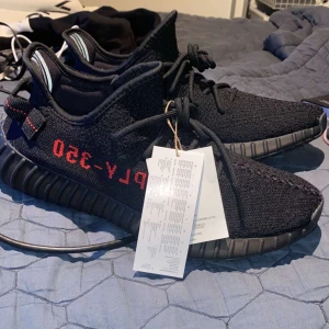 Adidas Yeezy Boost 350 V2 - Adidas Yeezy Boost 350 V2 i svart med röd text. Oanvända. Varken kvitto eller box medföljer.