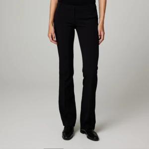Svarta bootcut byxor - Snygga svarta bootcut kostymbyxor med hög midja. Perfekta för en stilren look. KostymByxorna har en klassisk design med en lätt utsvängd passform. I modell Vilma / Vera,köpta för 500kr. Modell tall. Aldrig använda