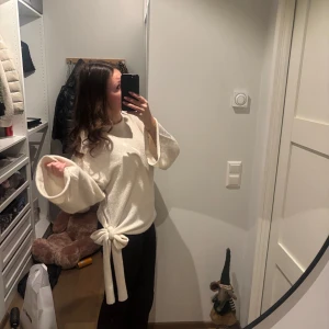 Vit tröja med knytband - Säljer en stilren vit tröja med långa ärmar och ett snyggt knytband i midjan. Perfekt för en chic och avslappnad look. Använd väldigt fåtal gånger och skicket är super
