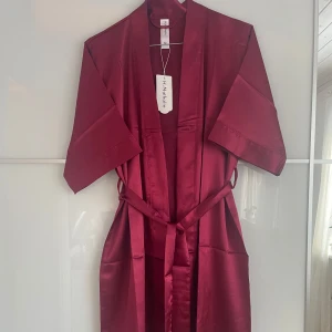 Vinröd kimono från missäy - Vinröd kimono från Missäy i satin med knytband i midjan