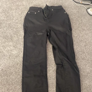 Svarta byxor från 157 - Snygga svarta byxor från 157 i storlek XS. Byxorna har en klassisk design med dragkedja och knappar. Perfekta för en stilren look.