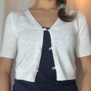 Vit kortärmad kofta - Säljer en söt vit kofta med korta ärmar och knappar framtill. Perfekt för lager-på-lager och passar till många olika outfits. Ett måste i garderoben!