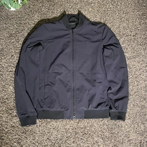 J.Lindeberg Jacka Windbreaker - Hej,  Här säljer jag en Jacka ifrån J.Lindeberg. Den är i storlek S och i ett grymt skick (utan tecken på användning) Hör av dig vid eventuella frågor!
