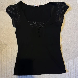 Svart topp med prickiga detaljer - Snygg svart topp med korta ärmar och prickiga detaljer. Super söt och trendig