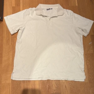 Vit kortärmad pikétröja från Ryvls som är perfekt för en svensk sommar - Säljer en stilren vit frotté pikétröja från Ryvls. Tröjan har en klassisk krage och korta ärmar, perfekt för en avslappnad look. Materialet känns mjukt och bekvämt mot huden.. Storlek 148-150 (ca 12 år) 