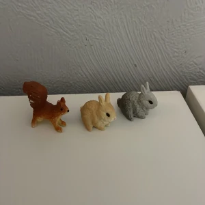 Schleich smådjur - Tre små djurfigurer i plast, en brun ekorre och två kaniner i beige och grått. Perfekta för dekoration eller lek.
