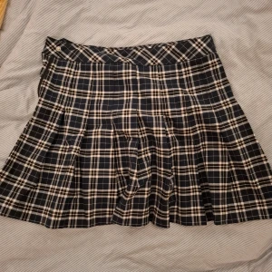 Rutig tennis kjol från H&M Divided - Snygg rutig kjol från H&M Divided i blått och vit. Kjolen har en klassisk design med ett rutigt mönster och är perfekt för en stilren look. 