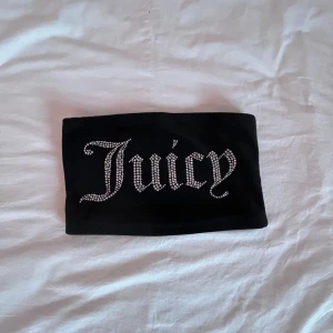Tubetop från Juicy Couture - Snygg svart tube top från Juicy Couture med glittrande stenar som bildar texten 'Juicy'. Perfekt för att ge en extra touch till din outfit. 