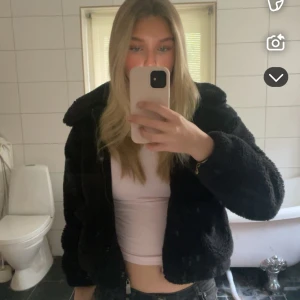 Svart teddyjacka - Mysig svart teddyjacka med dragkedja framtill. Jackan har en klassisk krage och långa ärmar, perfekt för kyligare dagar  och har praktiska fickor på framtill!