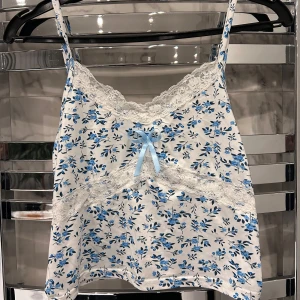 Blommig linne med spetsdetaljer - Säljer ett vit linne med blått blommönster och spetsdetaljer i storlek S. Köparen står för frakten!💗