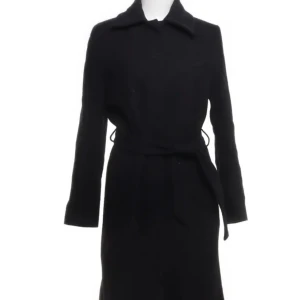 Svart kappa från Filippa K - Elegant svart kappa från Filippa K i storlek XS. Den har en klassisk design med knytband i midjan och långa ärmar. Det är en söm inuti jackan som har gått sönder men det syns inte 