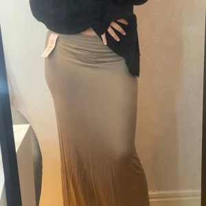 Nougatfärgad långkjol från Nelly - Säljer en nougatfärgad långkjol från Nelly i modellen 'Perfect Low Waist Maxi Skirt'. Aldrig kommit till användning.