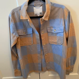 Rutig overshirt från 157 - Säljer en snygg rutig overshirt från 157 i blått och beige. Skjortan har långa ärmar och två bröstfickor med knappar. Perfekt för en avslappnad stil. Säljer pga för liten för mig❤️ strl: 160cm. Köpare står för frakten!🩷