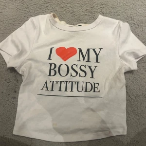 Vit t-shirt med tryck - Vit t-shirt med texten 'I ❤️ MY BOSSY ATTITUDE' i svart och rött. Kortärmad och perfekt för en självsäker look.