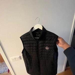 Svart quiltad väst från Colmar - Säljer en stilren svart quiltad väst från Colmar. Västen har en dragkedja framtill och en diskret logga på bröstet. Finns allt med lappar och även Qr kod. Bra väst o snygg men passade inte mig.       Kontakta mig för mer info!