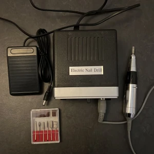 Elektrisk nagelfil med tillbehör - Säljer en elektrisk nagelfil med fotpedal och flera sliphuvuden. Perfekt för professionell nagelvård hemma. Inkluderar olika bits för filning och polering. Justerbar hastighetskontroll. 