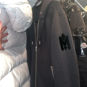 Svart hoodie från Moncler - Snygg svart hoodie från Mackage med dragkedja och justerbar huva. Den har en stor logotyp på ärmen och text på huvan. Perfekt för en casual look. Och väldigt varm och skön finns kvitto såklart från johnells s men stor i storleken