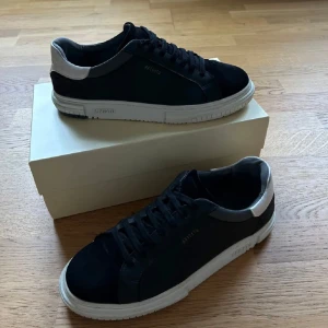 Svarta sneakers från Axel Arigato - Snygga svarta sneakers från Axel Arigato med vit sula och vit detalj vid hälen. Skorna har snörning och är tillverkade i mocka och skinn. Perfekt till att använda skorna i vintern men även året om. Nypris 2500kr och är i väldigt bra skick, Skriv för fler bilder😀!