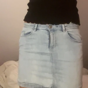 Ljusblå jeanskjol - Säljer en superfin ljusblå jeanskjol i kort modell. Den har en klassisk femficksdesign och stängs med knapp och dragkedja fram. Perfekt för sommardagar eller en avslappnad vårlook. Passar till allt från sneakers till sandaler!