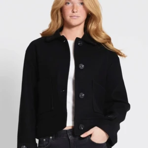 Kappa  - Snygg svart kappa i ull med stora knappar framtill. Den har en klassisk design med långa ärmar och två fickor. Perfekt för höst och vinter, och ger en stilren look till vilken outfit som helst. Köpt från lager 157. 